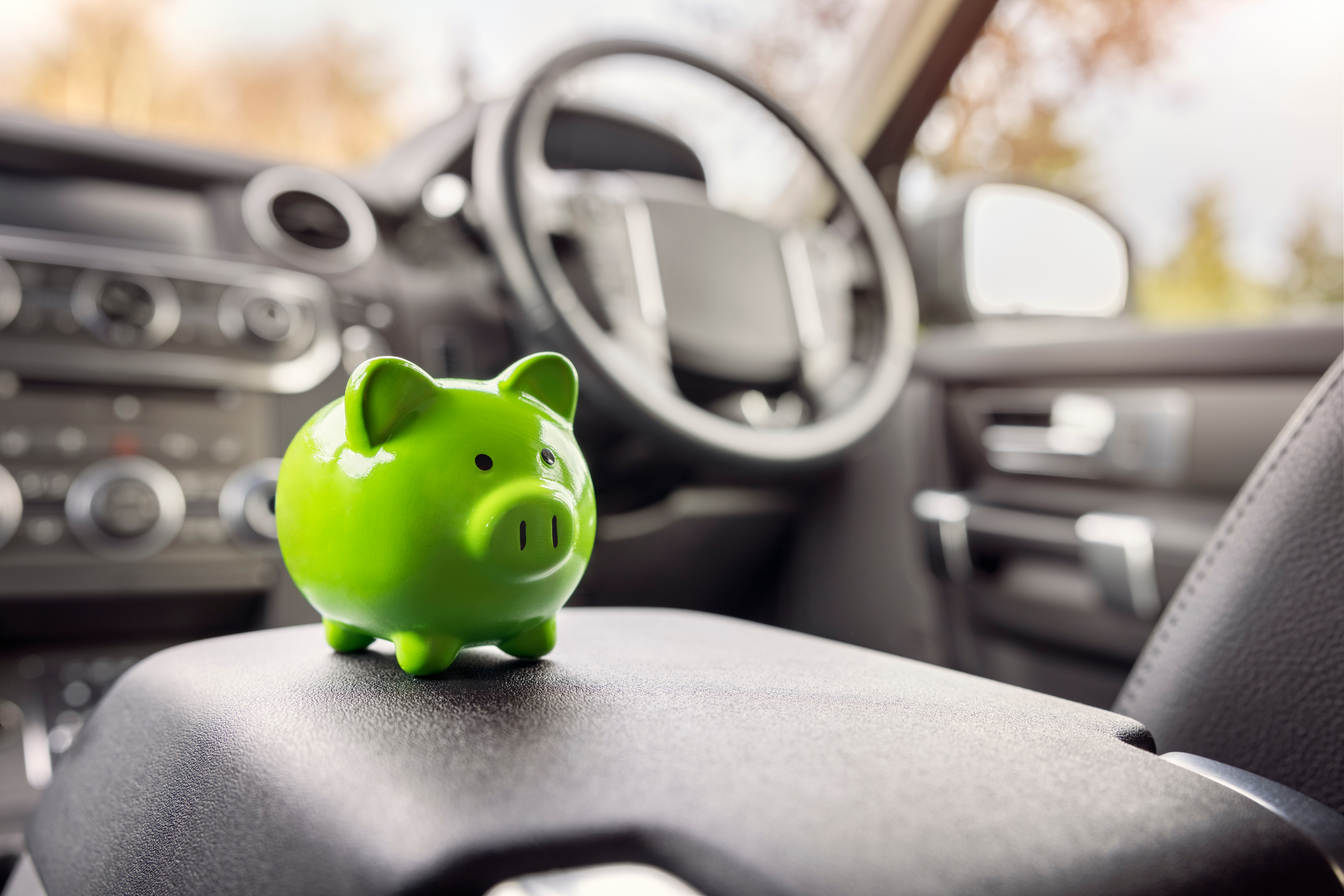 Car insurance vehicle value concept with piggy bank inside vehicle showing insurance cost savings and premium planning