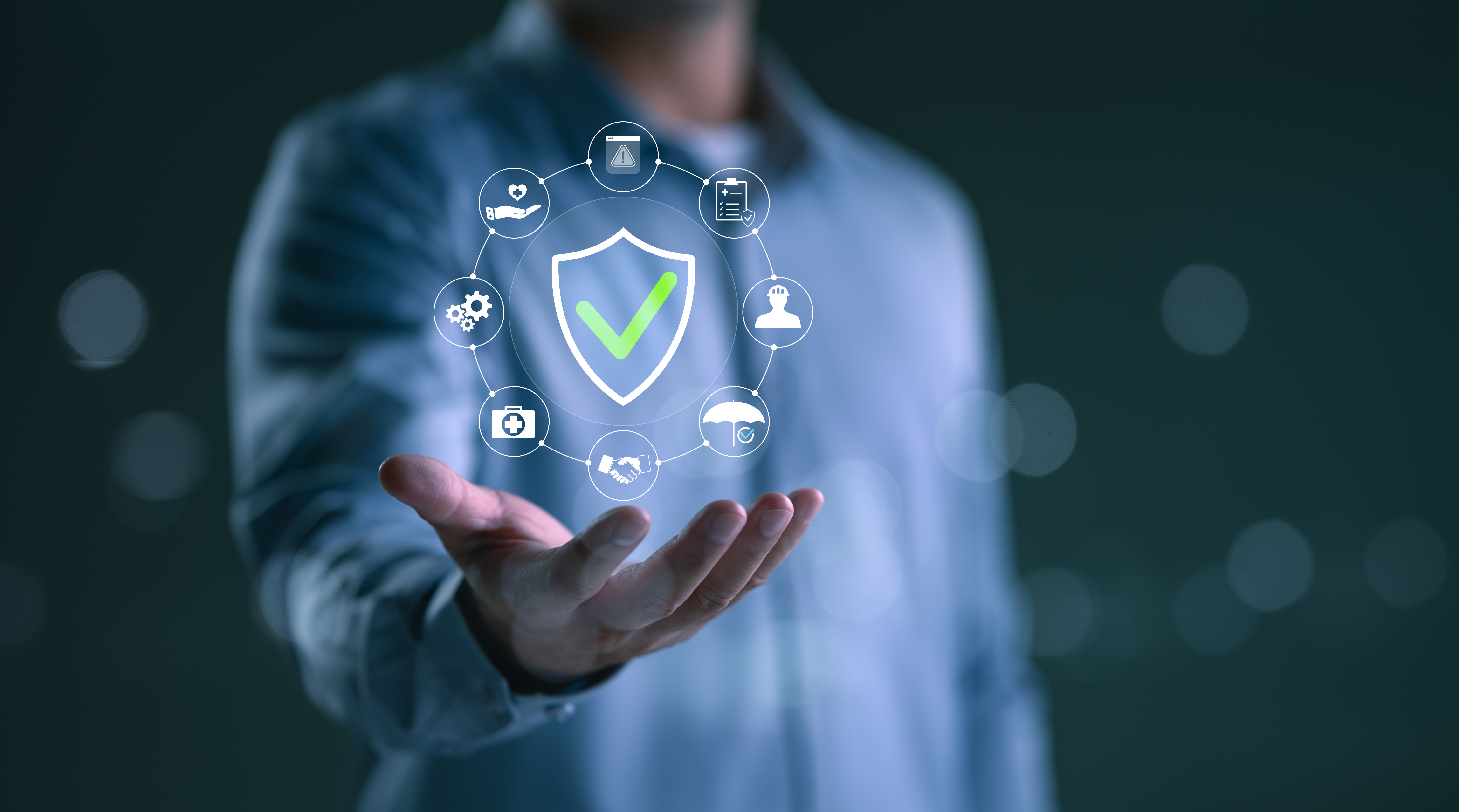 Insurance technology concept showing digital shield with checkmark and connected insurance service icons floating above executive's hand